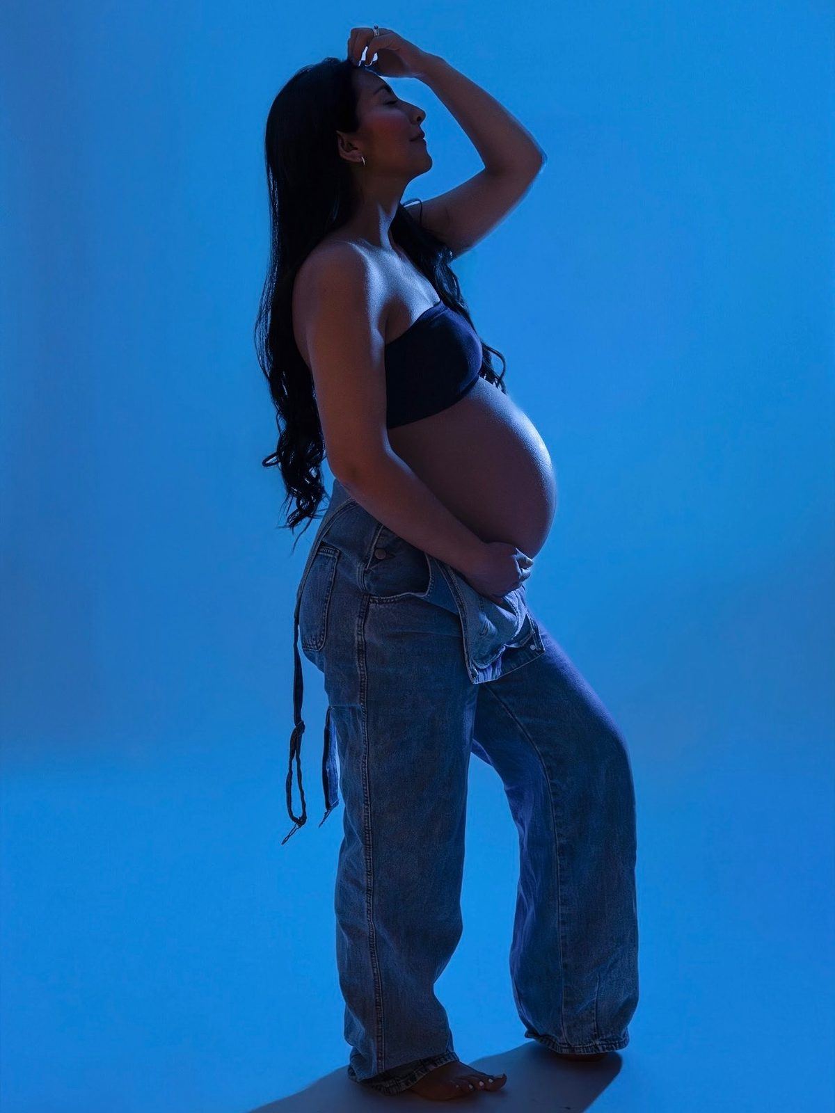 Maternity silhouette in denim against a blue cyclorama