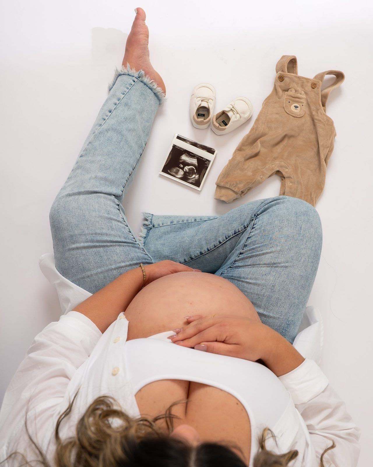 Overhead maternity flat-lay with baby clothes and an ultrasound